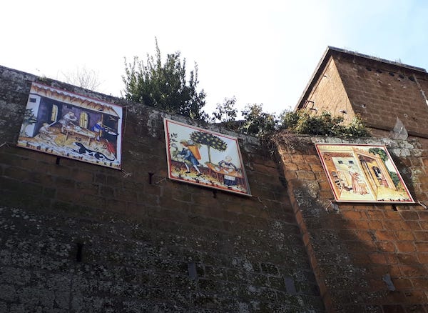 "Natività sospesa" su tetti e muri nel quartiere medievale, tra arazzi e quadri lignei