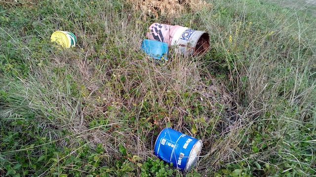 Discarica abusiva a Rocca Ripesena, secchi di vernice abbandonati nel verde